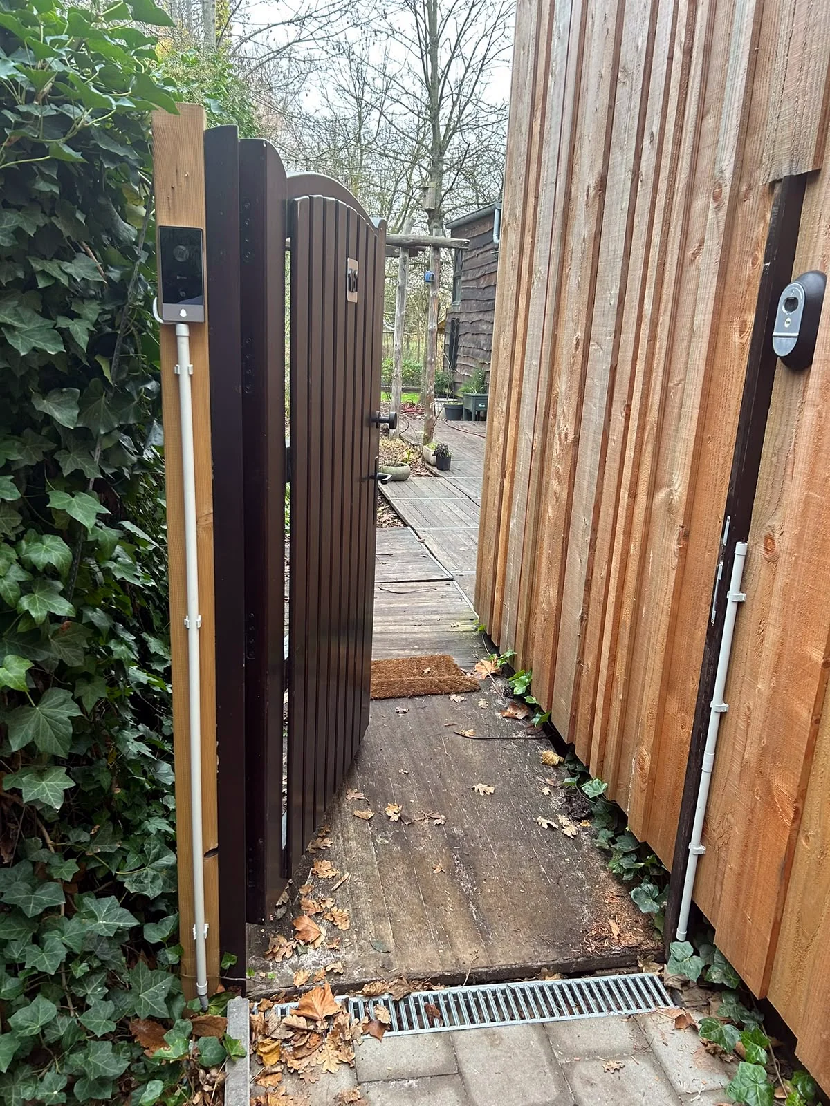 Videofoon met camera naast een houten tuinpoort